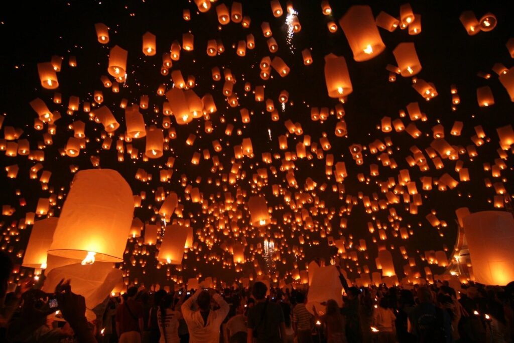 A crowd of people flying lights at night.