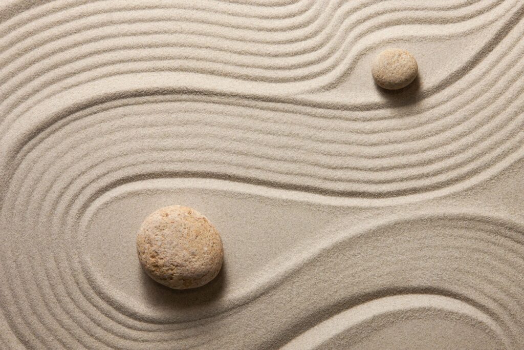 Two stones are sitting in the sand on a beach.